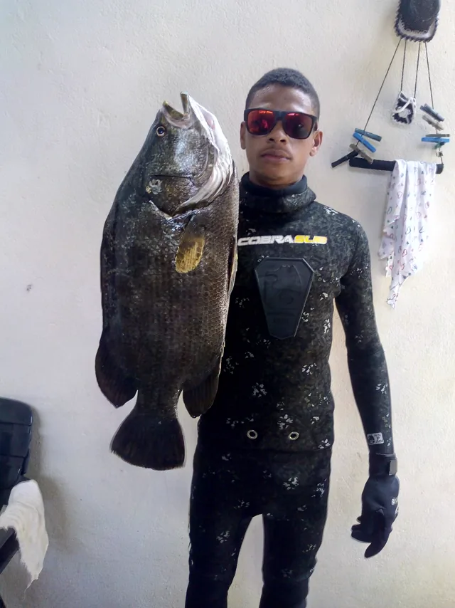 Filho de pescador artesanal com peixe